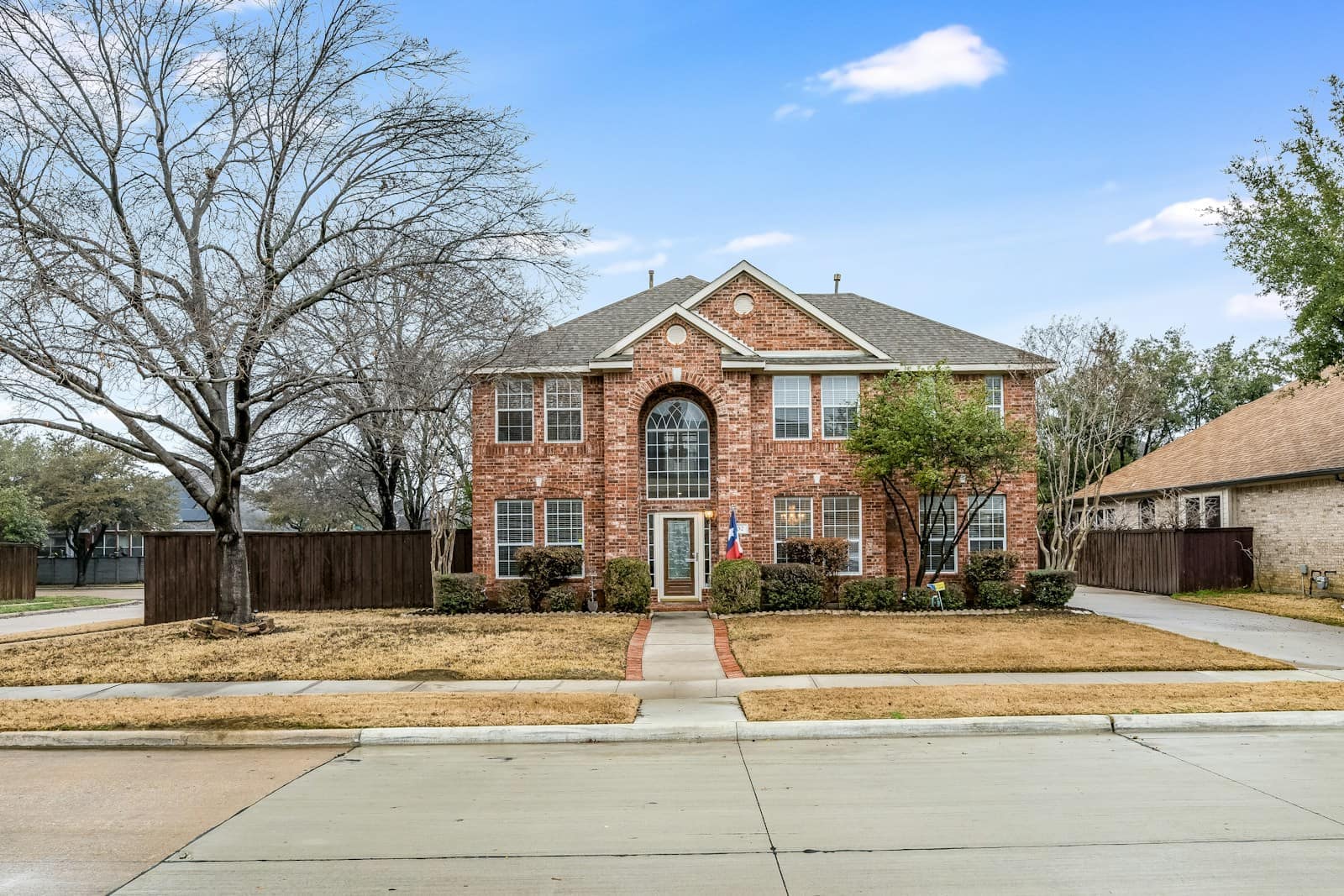 Two-story brick house with a wide front lawn and a shade tree