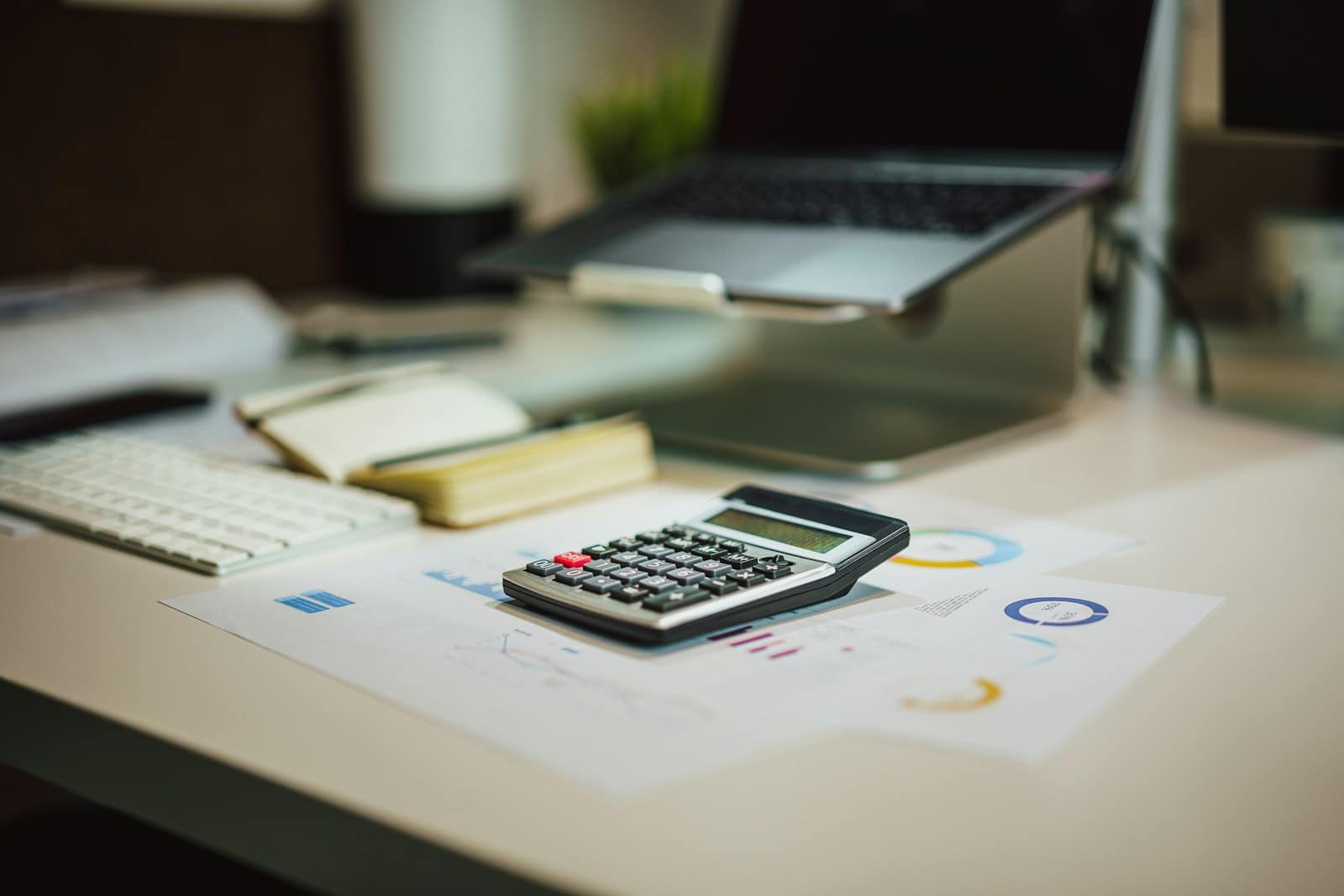 A calculator next to a laptop on a desk